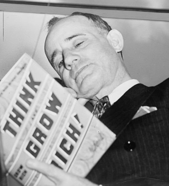 A photograph of Napoleon Hill, reading his book "Think and Grow Rich", taken in 1937