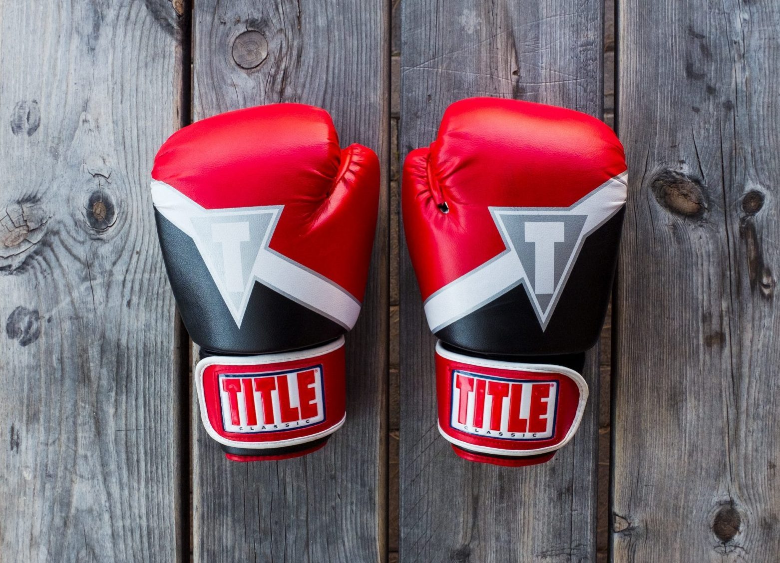 Red, white and black pair of boxing gloves on a bench.