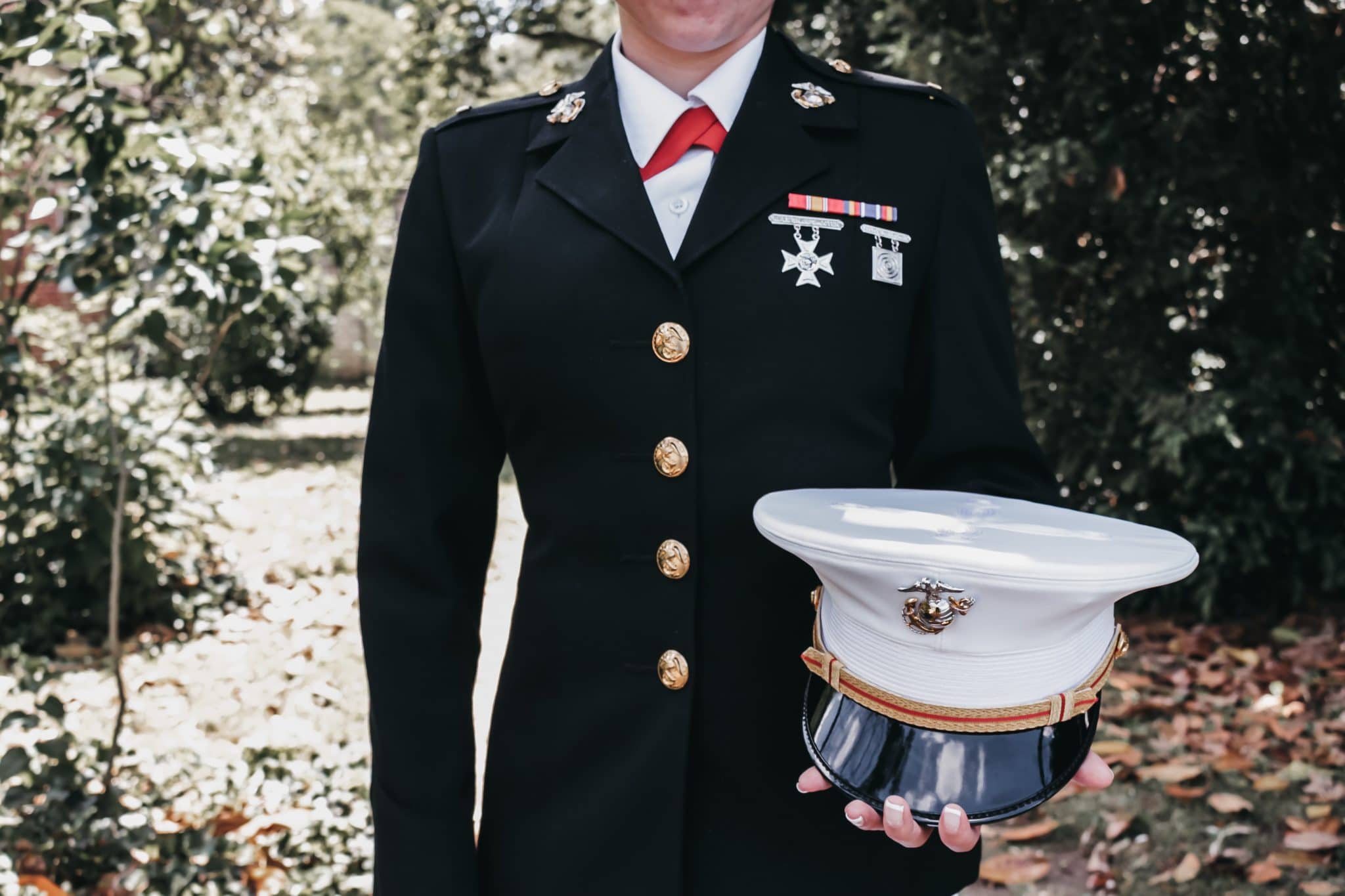 Photo of a woman from the US Marine Corps, in her uniform, holding her hat and smiling