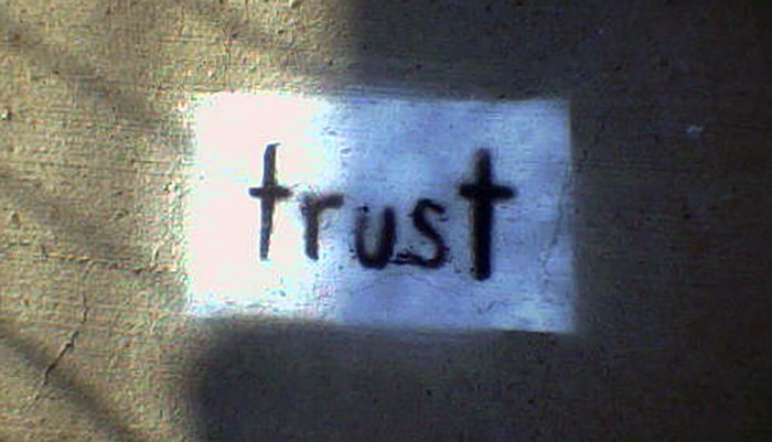 Graffiti Image on a wall with a writing that says "Trust."