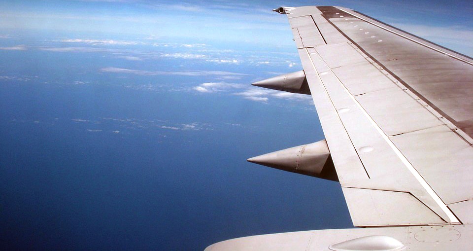 Photo of an aeroplane-wing taken from within the plane during flight, and the sky is blue.