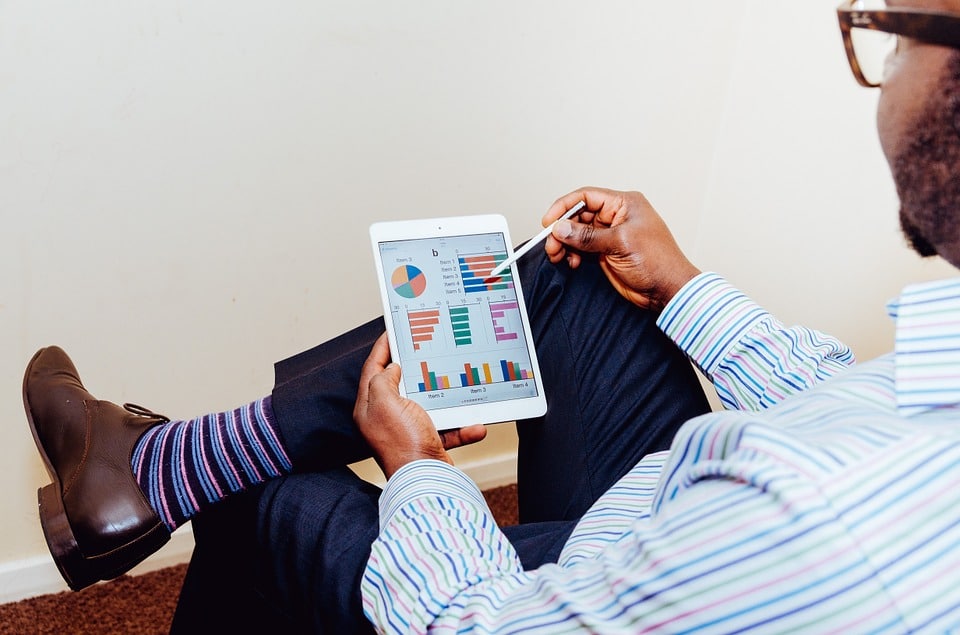 Photo of a businessman sitting on a sofa with funky socks using a tablet.