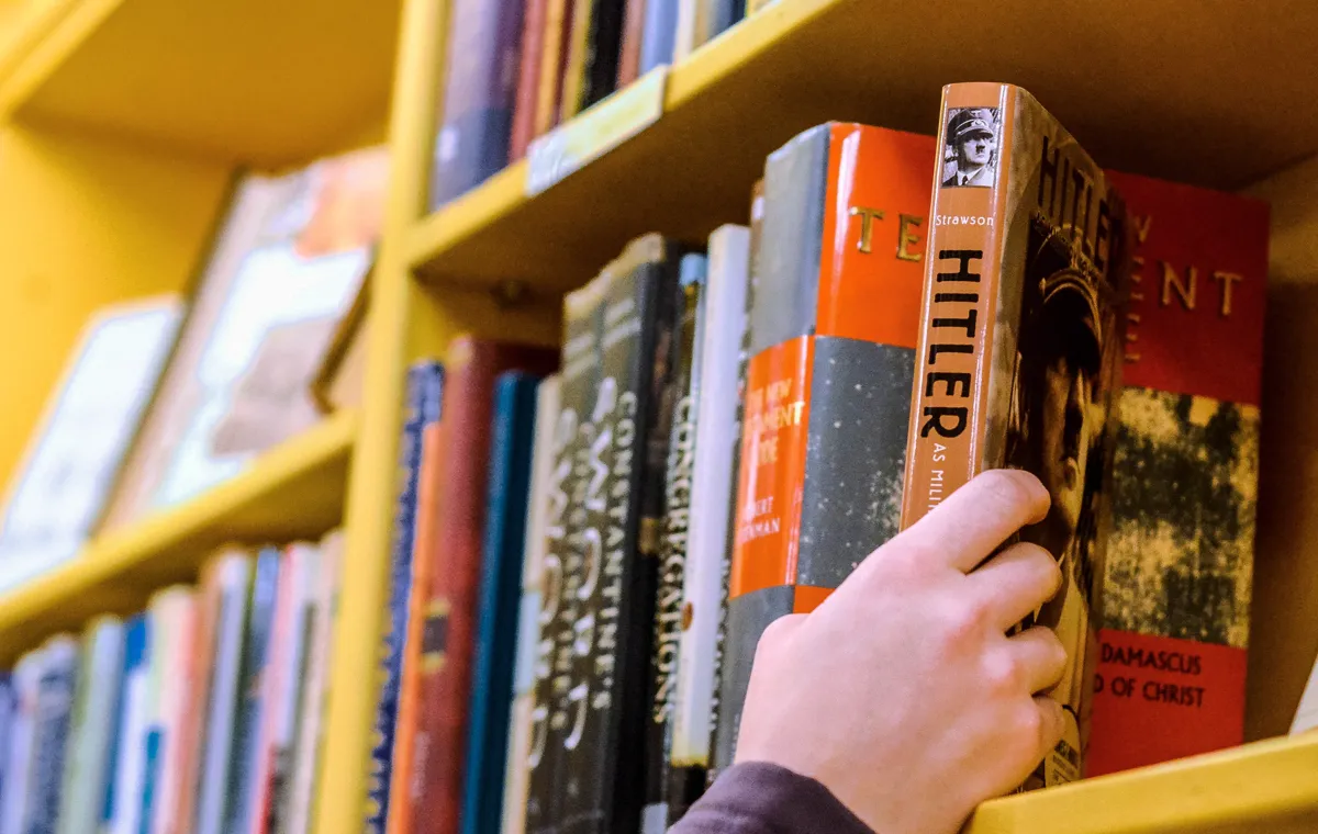 A photo of a person picking up a book of Hitler from a library.