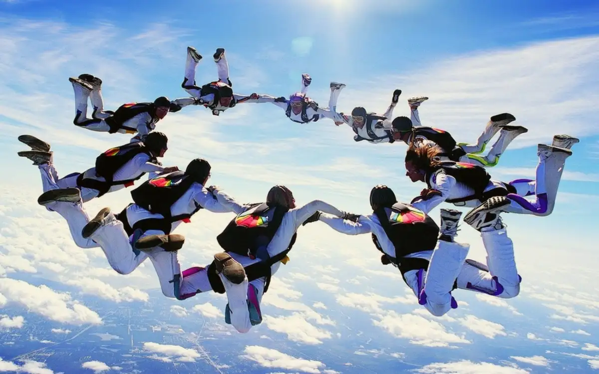 Photo of a team of parachuters collaborating in air.