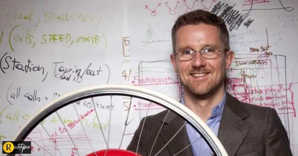 Professor Carlo Ratti holding a large bicycle wheel.