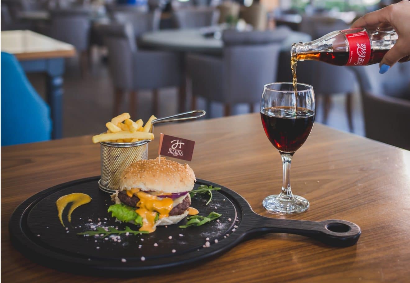 Woman drinking coca-cola with her burger and chips meal in a restaurant.