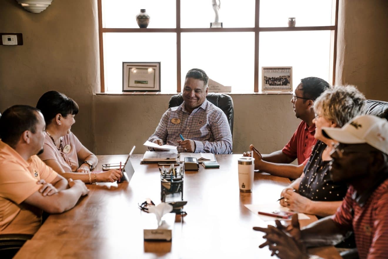 People sitting around wooden table in an office environment.