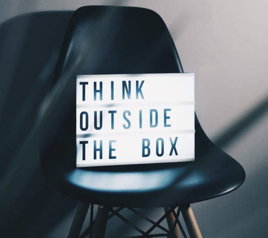 An office chair with a framed poster writing "think outside the box".