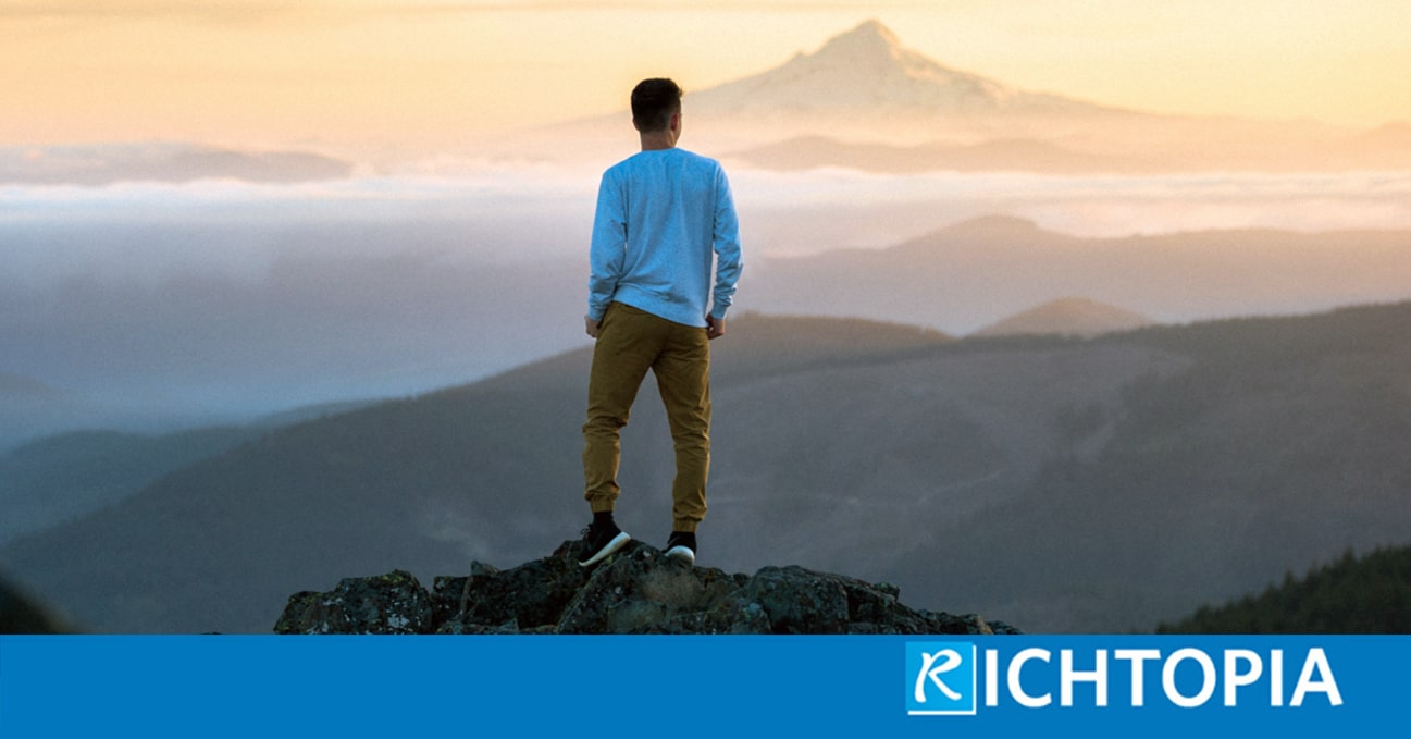 Man standing on top of a mountain looking a fantastic view with other mountains, sunset and clouds. Thinking as a thought-leader.