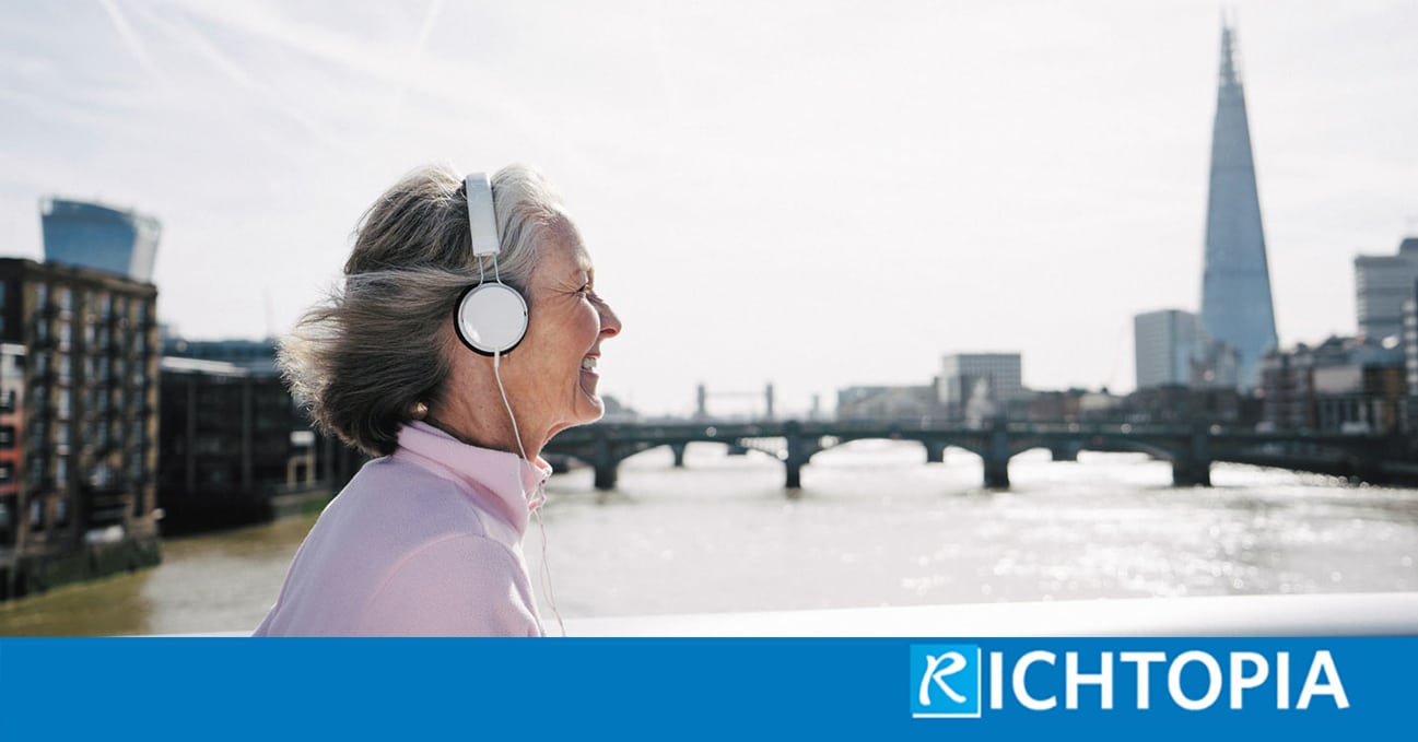 Photo of senior woman taking a walk through London listening to a podcast on her headphones.