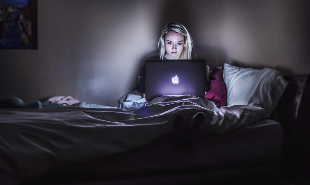 Woman sitting on bed with macbook reading about online security