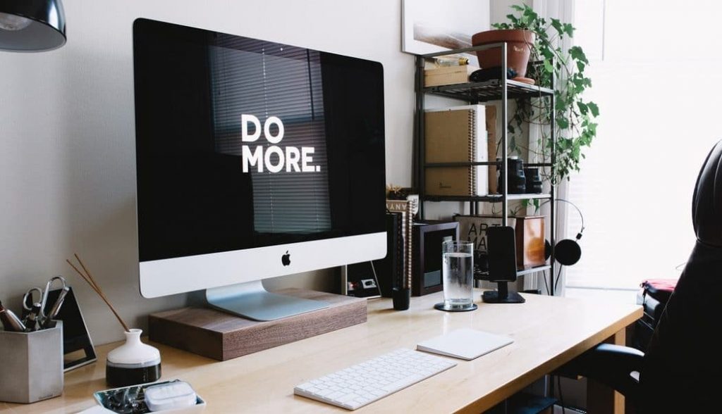 Photo of an Apple Desktop PC with wallpaper writing "Do More".