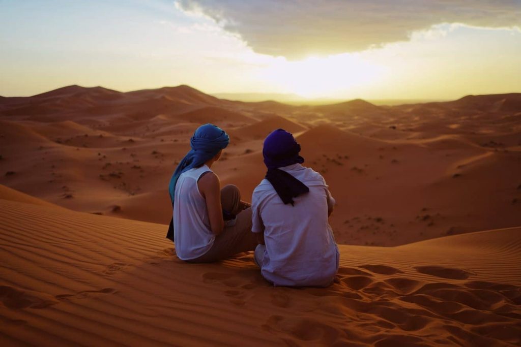 Two people sitting on the sand in an African desert.