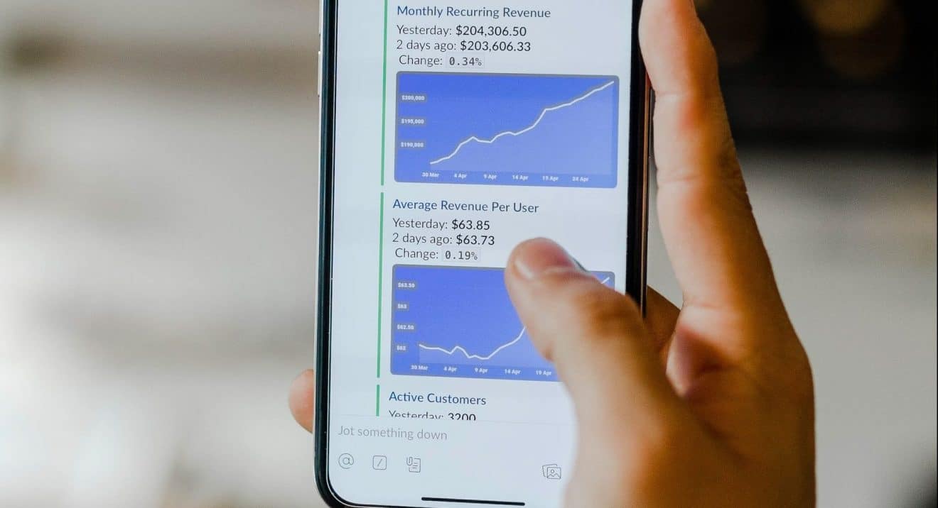 Man looking at his companies finances on his smartphone and seeing financial growth.