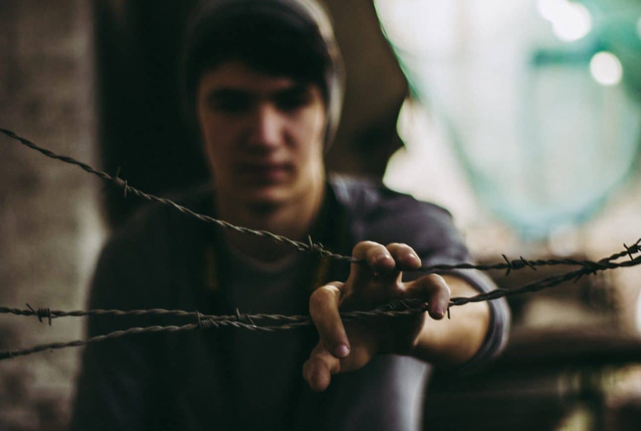 Photo of young man holding barbed wire