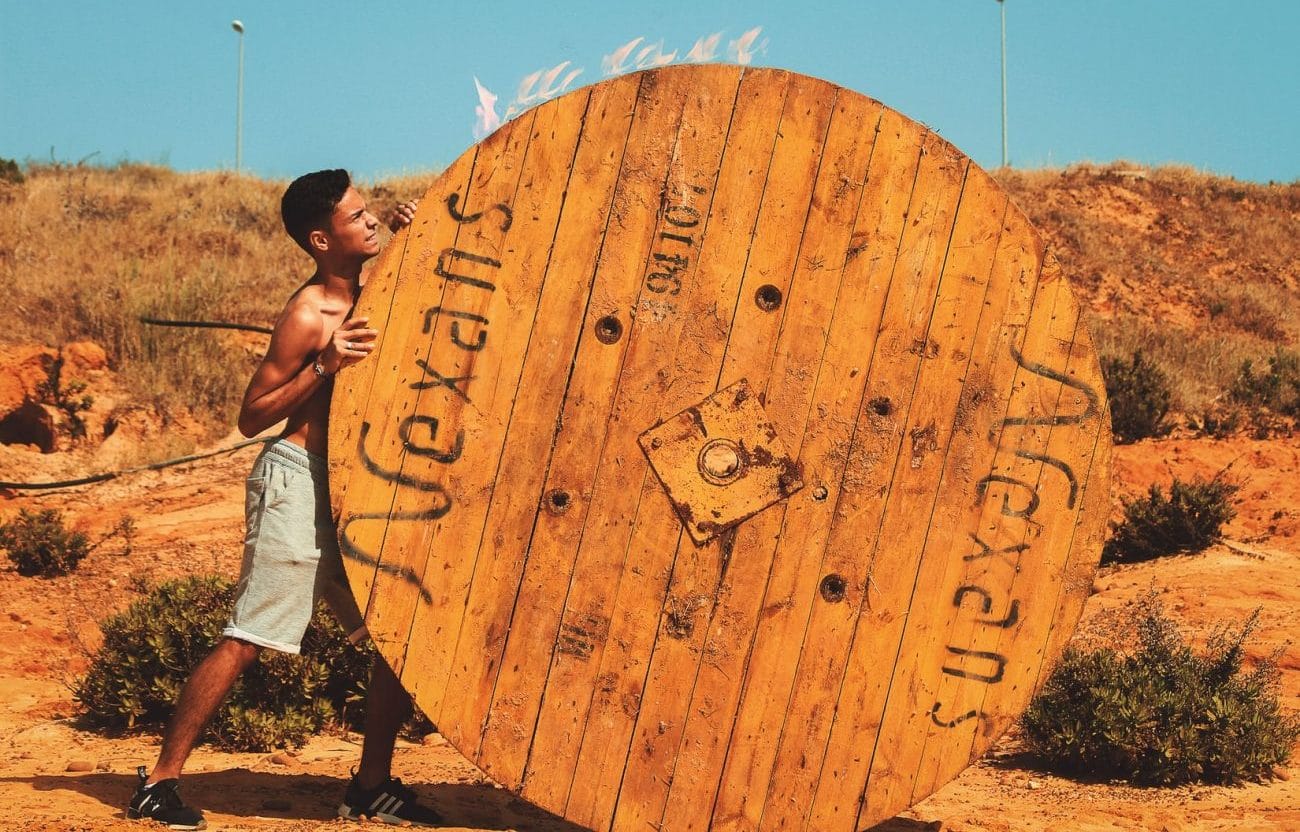 boy pushing barrel in a Mexican desert, on his own, without any help