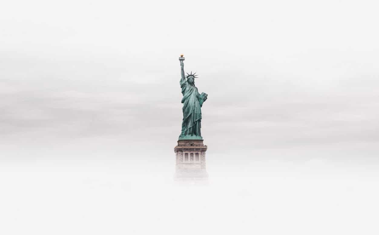 Statue of Liberty standing firm despite mist and clouds.