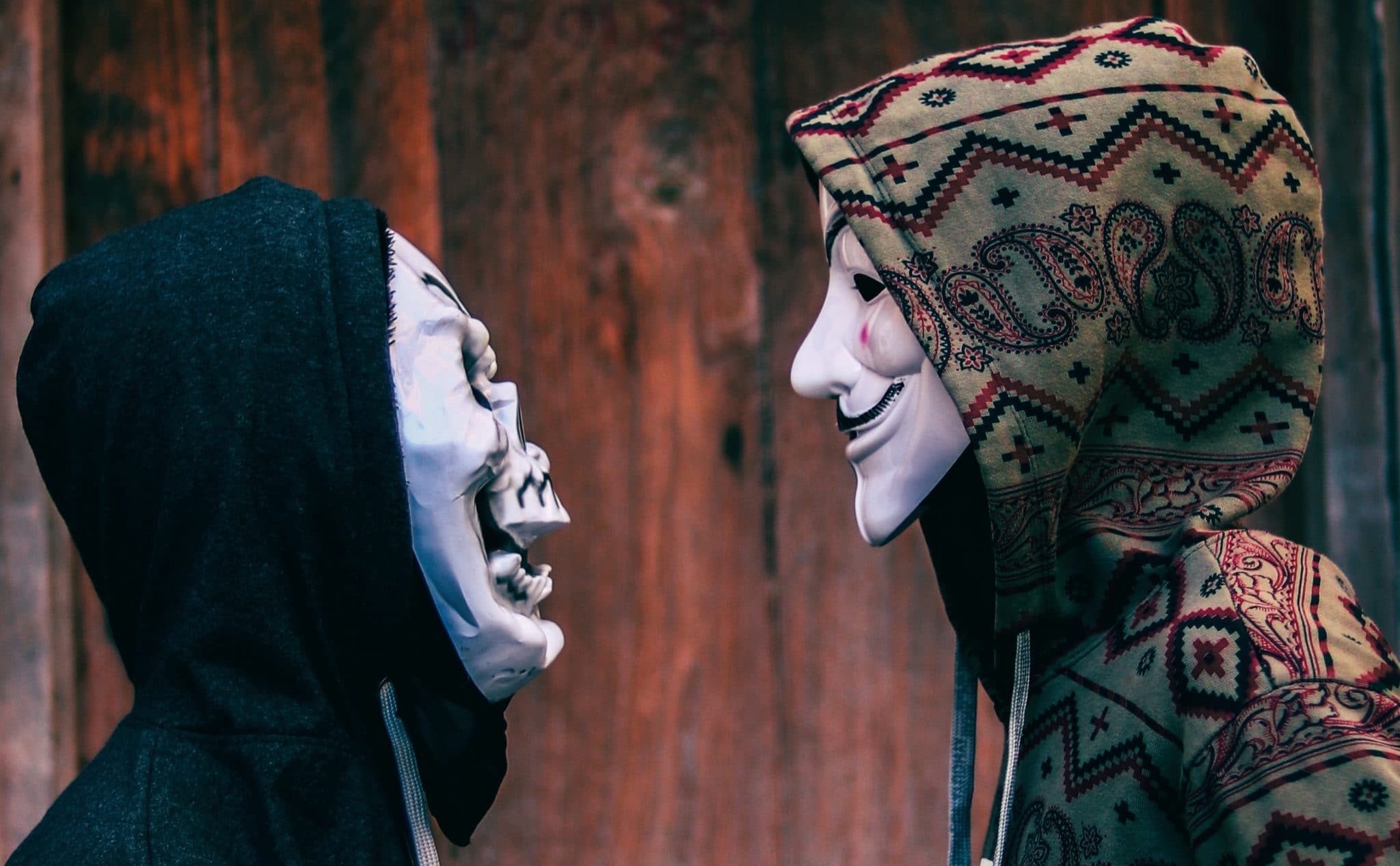 Two people negotiating whilst wearing masks and hoodies