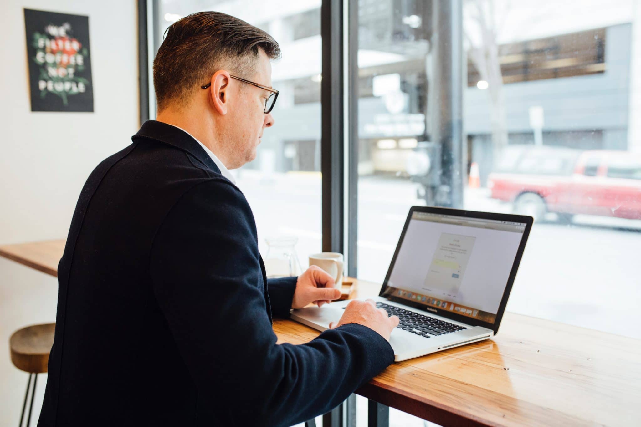 Photo of a man sitting on a desk using his laptop, on the LinkedIn Sales Navigator website.