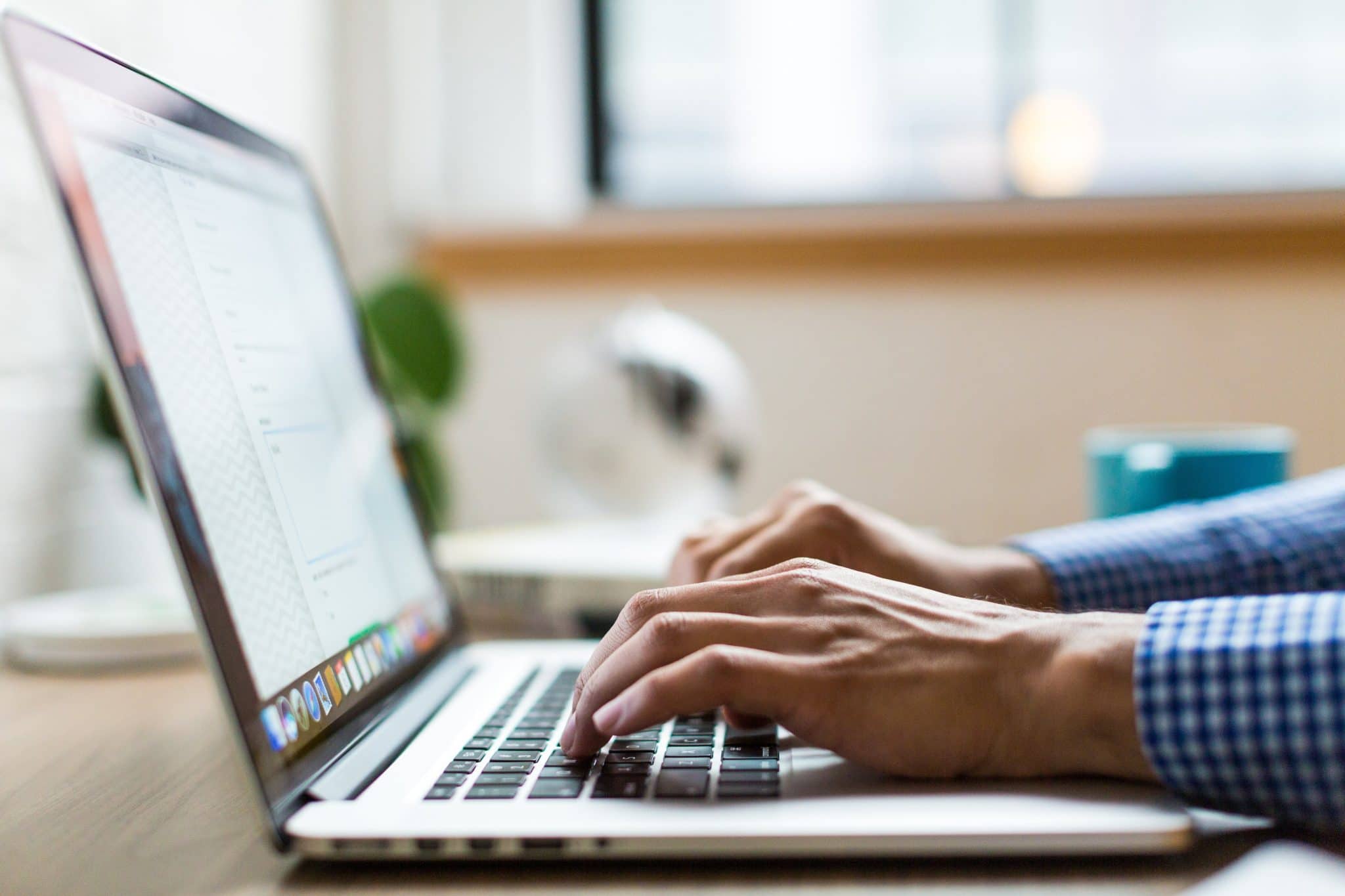 Close-up image of a man's hands typing on a laptop's keyboard.