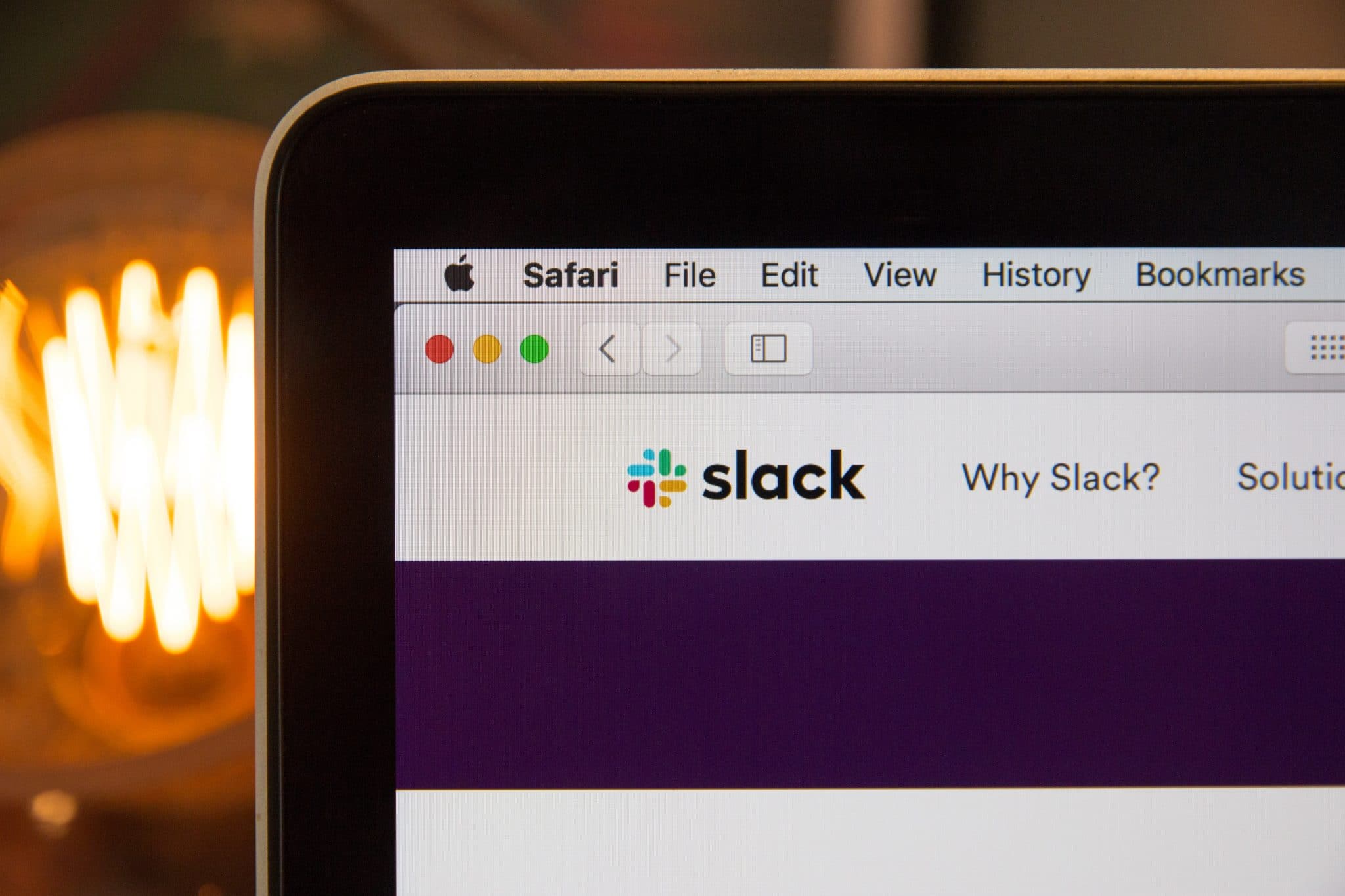 Close-up photo of a laptop screen focusing on the 'Slack' logo, taken on its website using the Safari browser.