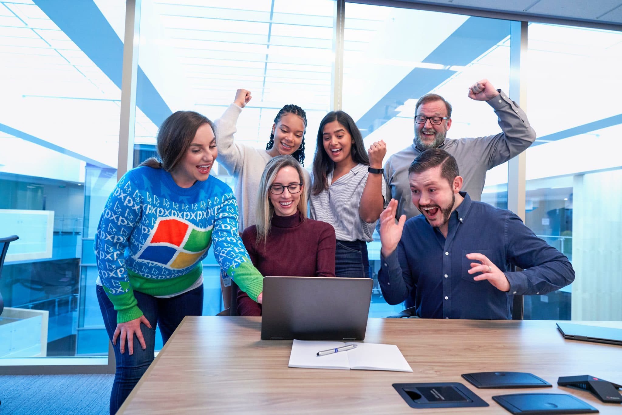 Team of people in an office celebrating their success in front of a laptop