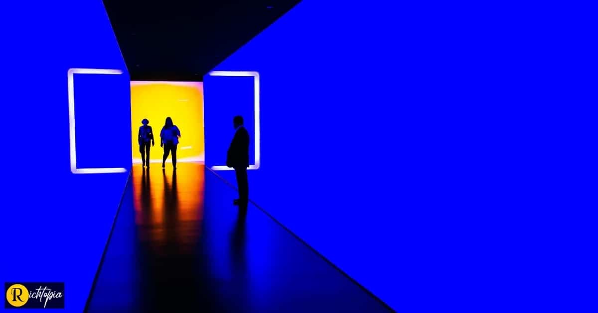 Team of people walking through corridor with blue walls from a well lit yellow area representing bright and innovative ideas