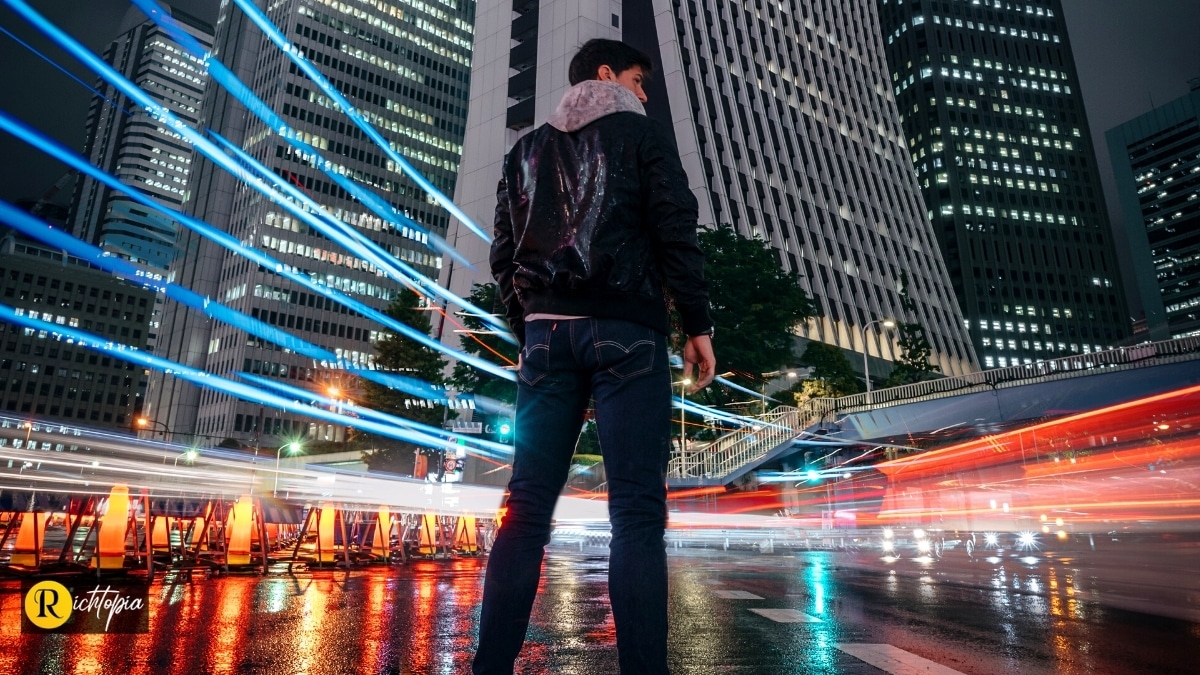 Photo of a man standing in the streets of Tokyo, Japan, with modern skycrapers around him and beams of light in the background.