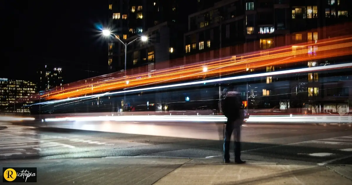 Photo of a man standing on the pavement looking at a road in Ontario, Canada, with timelapse light effect in the street.