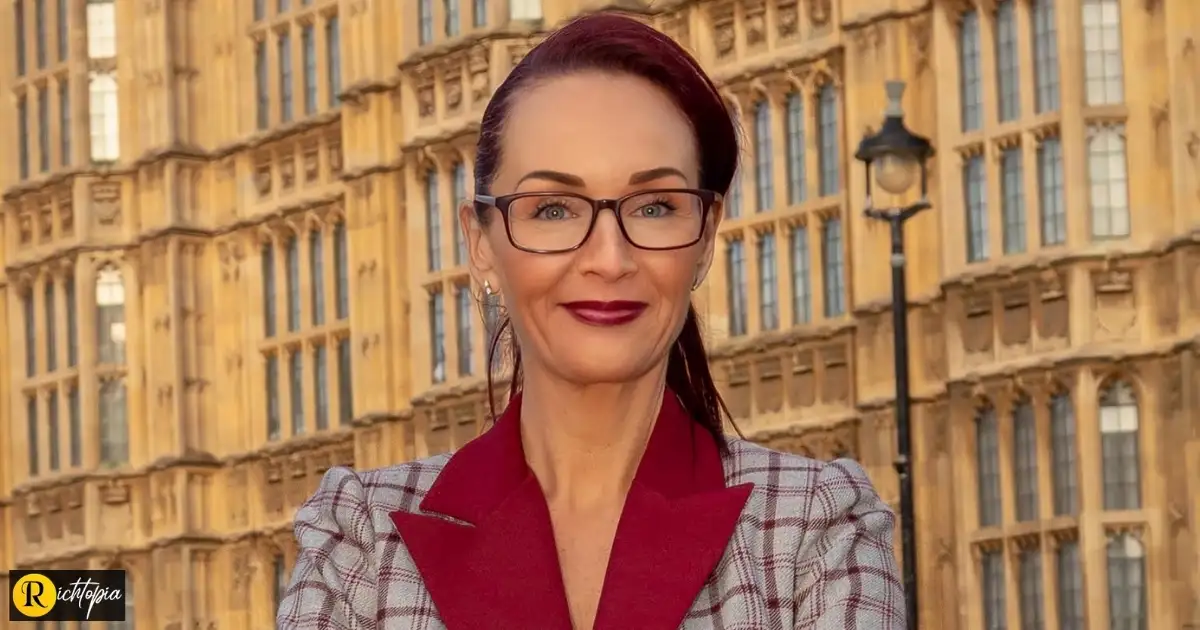 Chelsey Baker in grey & burgendy suit outside the UK House of Lords. Photo credit: Michael Slyfield.