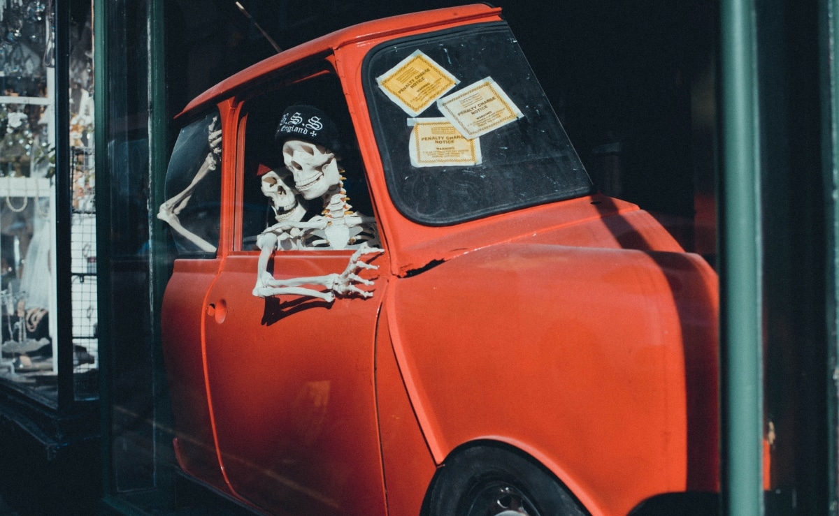 Shopfront display of skeletons driving a red car